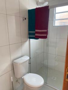 a bathroom with a toilet and a shower with towels at Casa da Praia: o mar a apenas 500 metros de você in Itanhaém