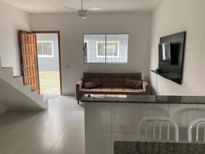 a living room with a couch and a television at Casa da Praia: o mar a apenas 500 metros de você in Itanhaém