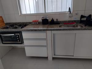 a kitchen with a sink and a stove top oven at Casa da Praia: o mar a apenas 500 metros de você in Itanhaém