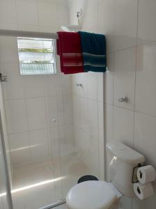 a white bathroom with a shower and a toilet at Casa da Praia: o mar a apenas 500 metros de você in Itanhaém