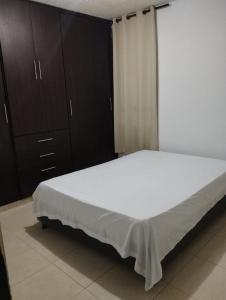 a bedroom with a large white bed and wooden cabinets at Apto de 3 habitaciones con ventiladores y parqueadero comunal in Valledupar