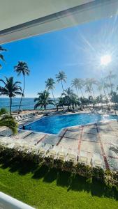 a view of a swimming pool with palm trees and the ocean at Promo_viviendas Sol y Mar in San Pedro de Macorís