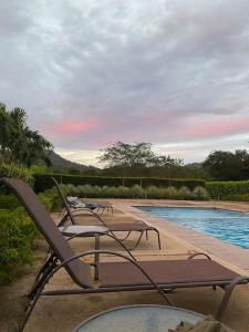 a row of lounge chairs next to a swimming pool at Casa Pacifico 46 Tamarindo in Santa Cruz