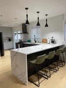 a kitchen with a large white island with bar stools at Modern Home for 10+ with Hot Tub! in Ottawa