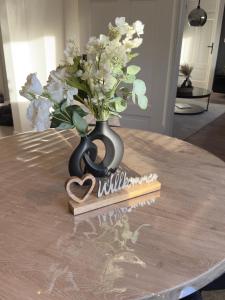 a black vase with a bouquet of flowers on a table at Belm Ferienwohnung am Bach in Belm