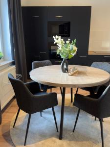 a table with chairs and a vase with flowers on it at Belm Ferienwohnung am Bach in Belm