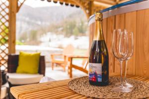 a bottle of wine and two glasses on a table at Le Chalet Bed&Bath -Chez Les Alfreds in Soubey