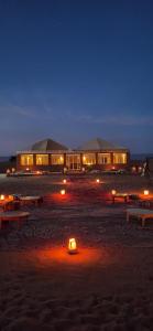 a building on a beach at night with lights at Sun Bivouac Chegaga in El Gouera