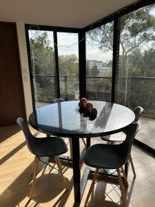 a dining room table with chairs and a large window at Residencial Chicle D401 in Mexico City