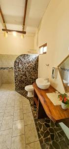a bathroom with a sink and a stone wall at Tarcoles Birding Lodge in Tarcoles