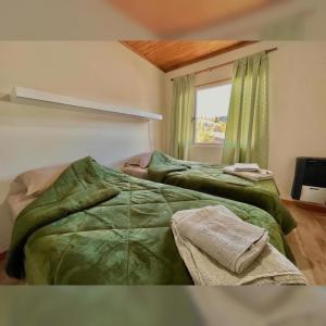 2 camas verdes en una habitación con ventana en Sauce Tempo, en Esquel
