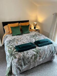 The Hideaway Holywell في هوليويل: سرير عليه وسائد خضراء في غرفة النوم