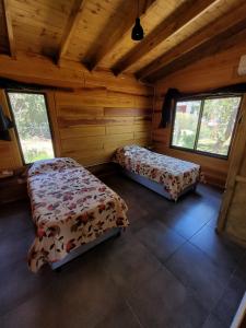 サンタ・ロサ・デ・カラムチタにあるSueño Serranoのログキャビン内のベッド2台が備わる部屋です。