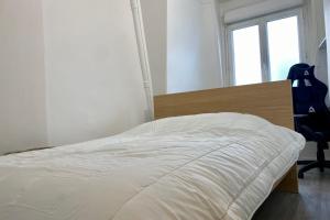 een slaapkamer met een bed, een stoel en een raam bij Cozy haven of peace ideal for a romantic stay in Saint-Mandé
