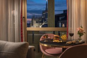 a room with a table with a burger and a glass of wine at NH Collection Milano President in Milan