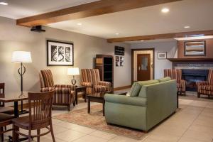 sala de estar con sofá, sillas y chimenea en Country Inn & Suites by Radisson, Winnipeg, MB en Winnipeg