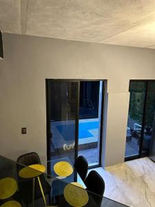 テキーラにあるCasa Landeros y Osunaのガラスのテーブルと椅子、窓が備わる客室です。