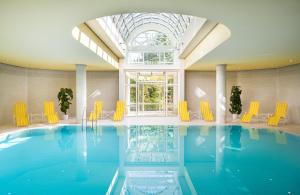 uma piscina com cadeiras amarelas e uma grande janela em Leonardo Hotel Weimar em Weimar