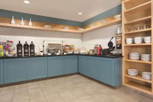 Country Inn & Suites by Radisson, Fresno North, CA في فريسنو: مطبخ مع خزائن زرقاء وأطباق على الأرفف