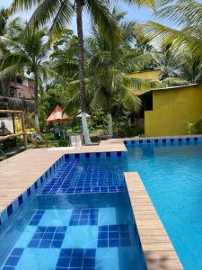une piscine bleue avec des palmiers en arrière-plan dans l'établissement Pousada Sol da Ilha, à Igrapiúna