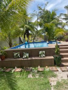 a swimming pool in a yard with pillows on a bench at Pousada Sol da Ilha in Igrapiúna