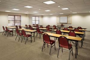 Country Inn & Suites by Radisson, Louisville East, KY في لويزفيل: قاعة اجتماعات مع طاولات وكراسي وشاشة