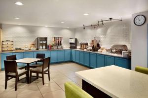 cocina con armarios azules, mesa y sillas en Country Inn & Suites by Radisson, Louisville East, KY, en Louisville