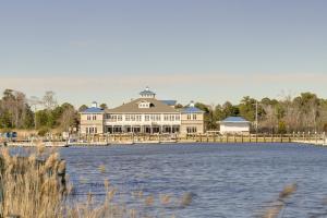 a large white building with a dock next to a body of water at Waterfront Ocean Pines Vacation Home with Boat Dock! in Ocean Pines