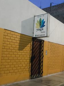 une porte menant à un bâtiment avec un panneau de studio de yoga dans l'établissement Casa - Hospedaje Munay Ki - Yoga -, à Pisco