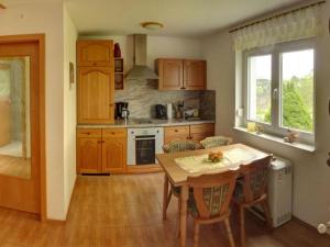una cocina con armarios de madera y una mesa con sillas. en Holiday home Oertel Häusl 