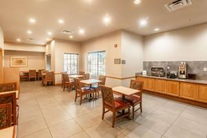 a restaurant with tables and chairs and a kitchen at Country Inn & Suites by Radisson, El Dorado, AR in El Dorado