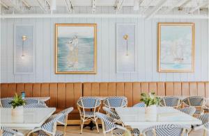 a restaurant with white tables and chairs and pictures on the wall at The Lighthouse Boutique Hotel in Port Isabel