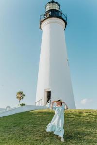 une femme en robe blanche debout devant un phare dans l'établissement The Lighthouse Boutique Hotel, à Port Isabel