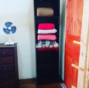 a black closet with a pile of towels and a fan at CHALÉ ALPiNO MONTANHA MÁGICA in São Thomé das Letras