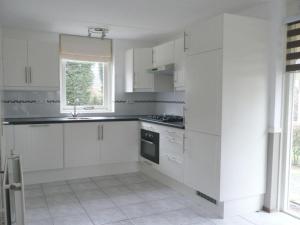 cocina blanca con armarios blancos y ventana en Holiday apartment Zonnewende 16, en Sint Maartensvlotbrug