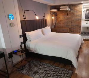 a bedroom with a large white bed and a brick wall at Faranda Collection Bogota, a member of Radisson Individuals in Bogotá