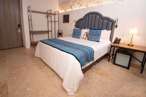 a bedroom with a large bed with blue and white pillows at Hotel Casa La Factoria by Faranda Boutique, a member of Radisson Individuals in Cartagena de Indias
