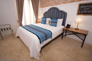 sypialnia z łóżkiem z niebieskimi poduszkami i stołem w obiekcie Hotel Casa La Factoria by Faranda Boutique, a member of Radisson Individuals w mieście Cartagena de Indias