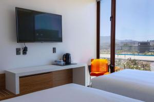 a bedroom with a desk with a tv on the wall at Park Inn by Radisson Los Olivos de Vallenar in Vallenar