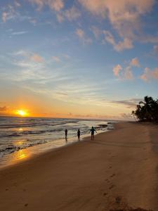 3 osoby spacerujące po plaży o zachodzie słońca w obiekcie Blue House Barra grande w mieście Barra Grande