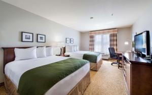 a hotel room with two beds and a flat screen tv at Country Inn & Suites by Radisson, Greeley, CO in Greeley