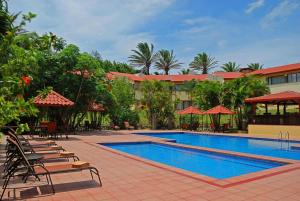 una piscina con tumbonas y un hotel en Country Inn & Suites by Radisson, San Jose Aeropuerto, Costa Rica en San José