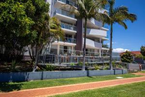 a building with palm trees in front of it at 'Sage' at The Crest - Spacious ground floor apartment in Forster