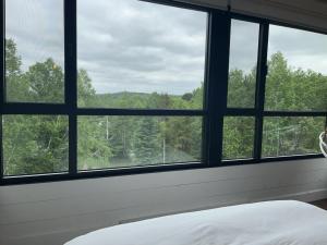 a bedroom with a window looking out at the forest at Le201chaletlactaureau in Saint-Michel-des-Saints