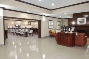 a lobby with a waiting area with tables and chairs at Country Inn & Suites by Radisson, Pensacola West, FL in Pensacola