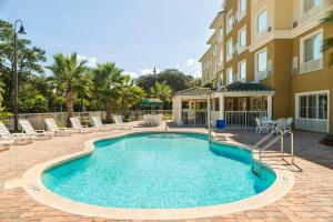 a swimming pool with chairs and a building at Country Inn & Suites by Radisson, Port Orange-Daytona, FL in Port Orange