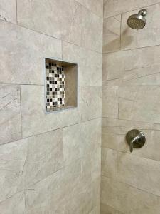 a shower with a tile wall with a window at Neston in Hamilton