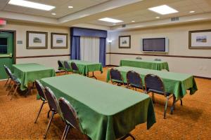 einen Konferenzraum mit grünen Tischen und Stühlen sowie einem Bildschirm in der Unterkunft Country Inn & Suites by Radisson, Port Charlotte, FL in Port Charlotte