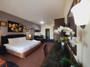 a hotel room with a bed and a desk with flowers at Rainbow paradise beach front in Tanjung Bungah