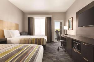 a hotel room with two beds and a flat screen tv at Country Inn & Suites by Radisson, Panama City Beach, FL in Panama City Beach